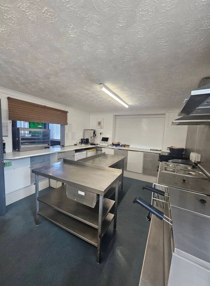 Commercial catering kitchen with stainless steel prep tables and range cleaned down