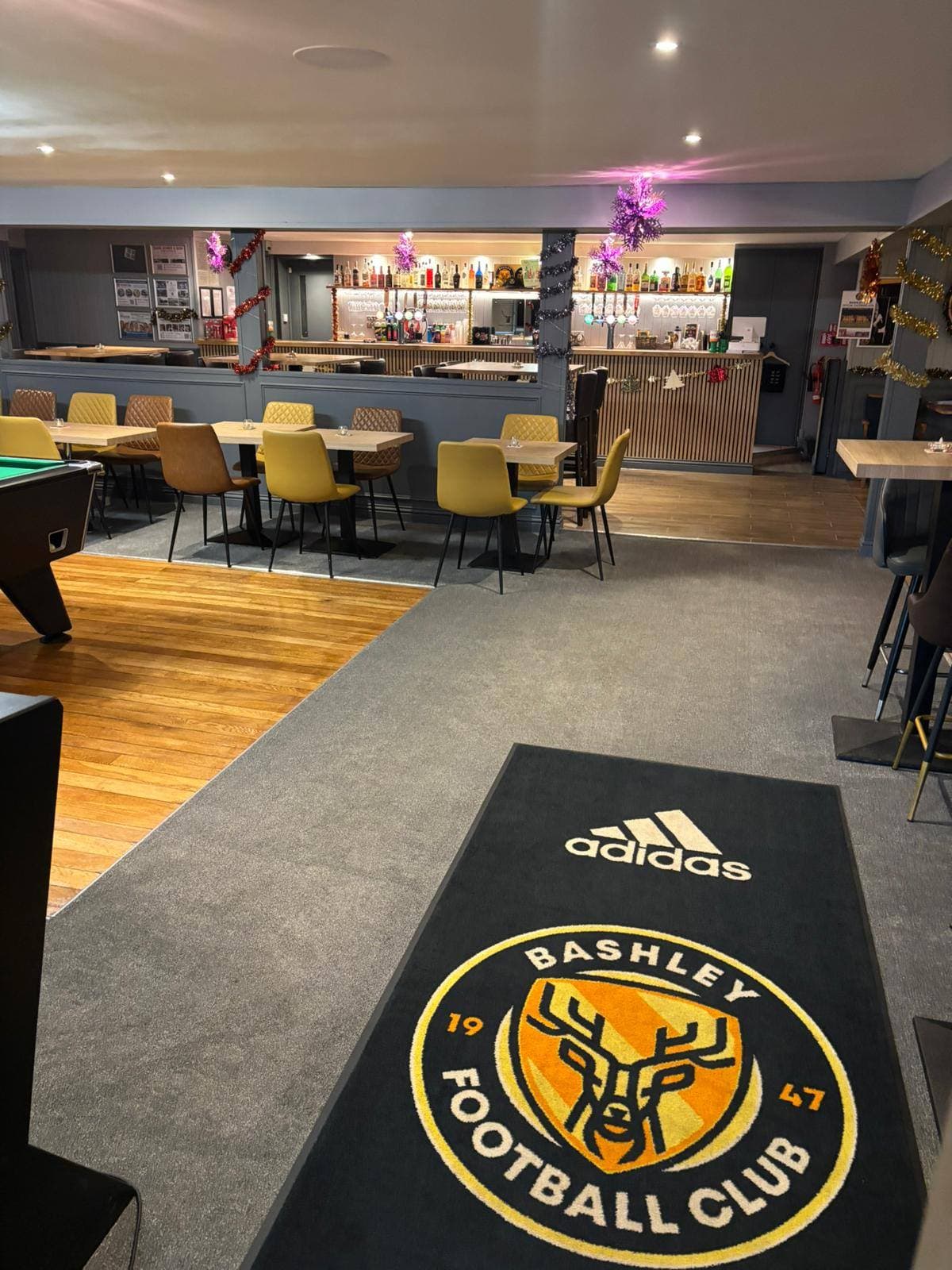 Football club bar and lounge with a pool table, dining tables and polished floor after a clean