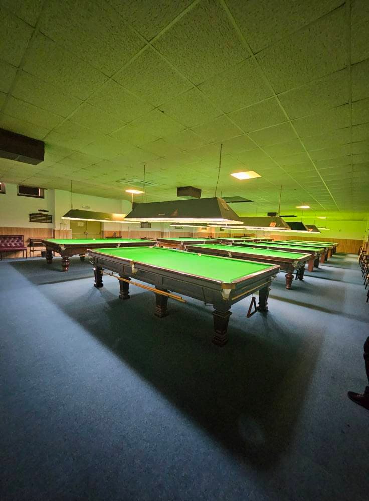 Snooker club hall with rows of full-size tables and clean carpet after a deep clean