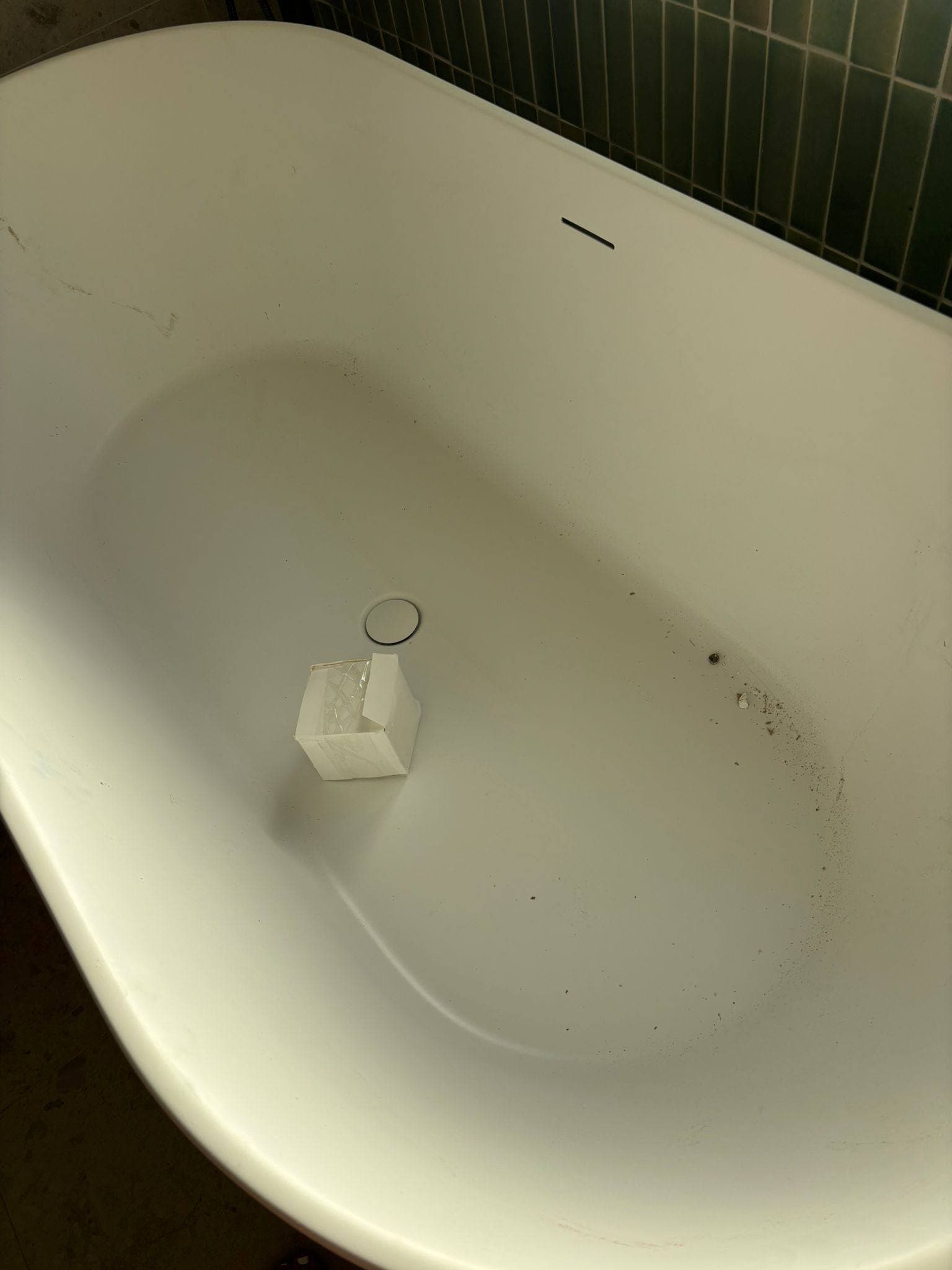 Freestanding bath left dusty after install, with packaging debris in the basin