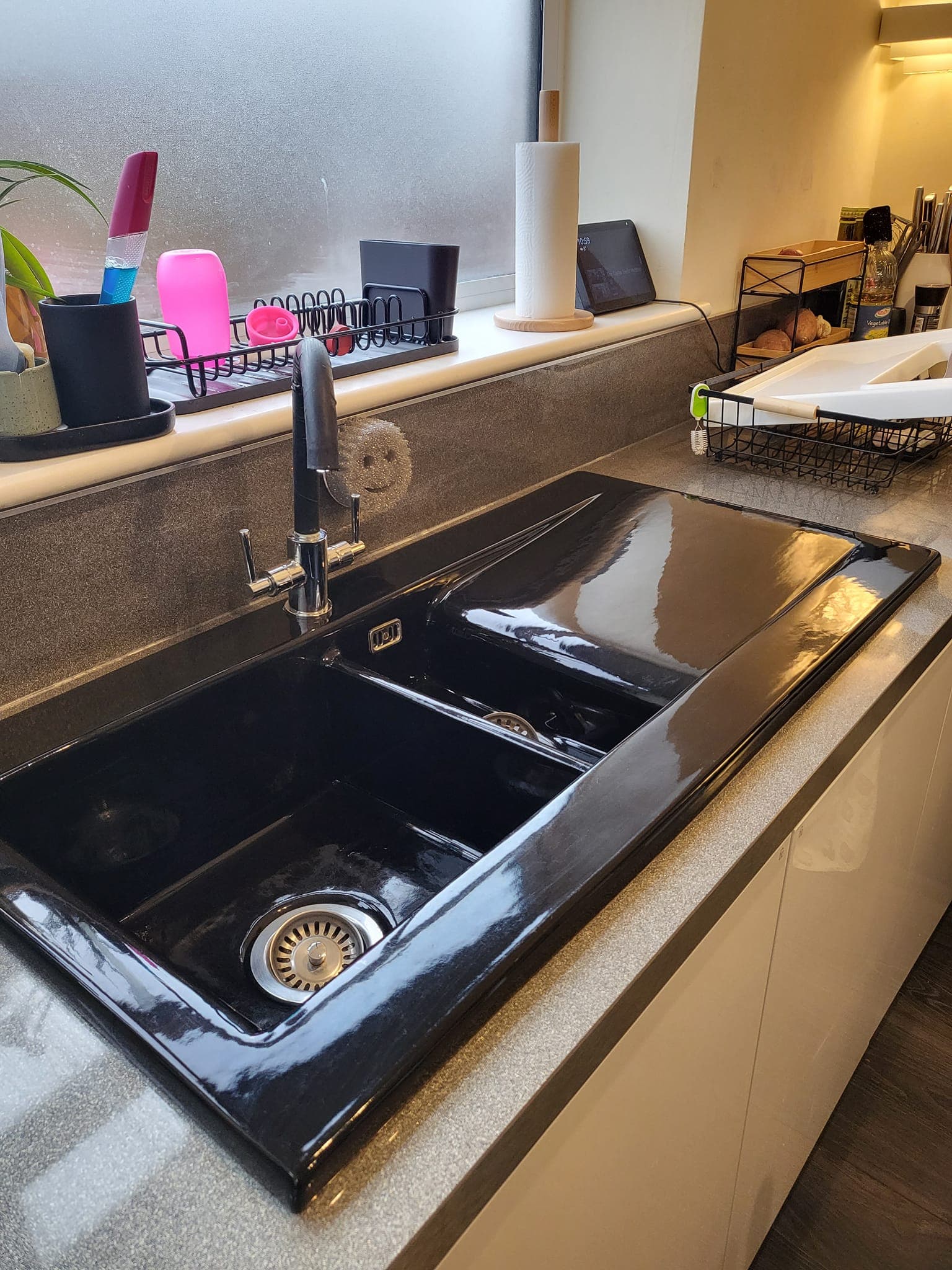 The same black composite sink cleaned and polished to a high-gloss finish