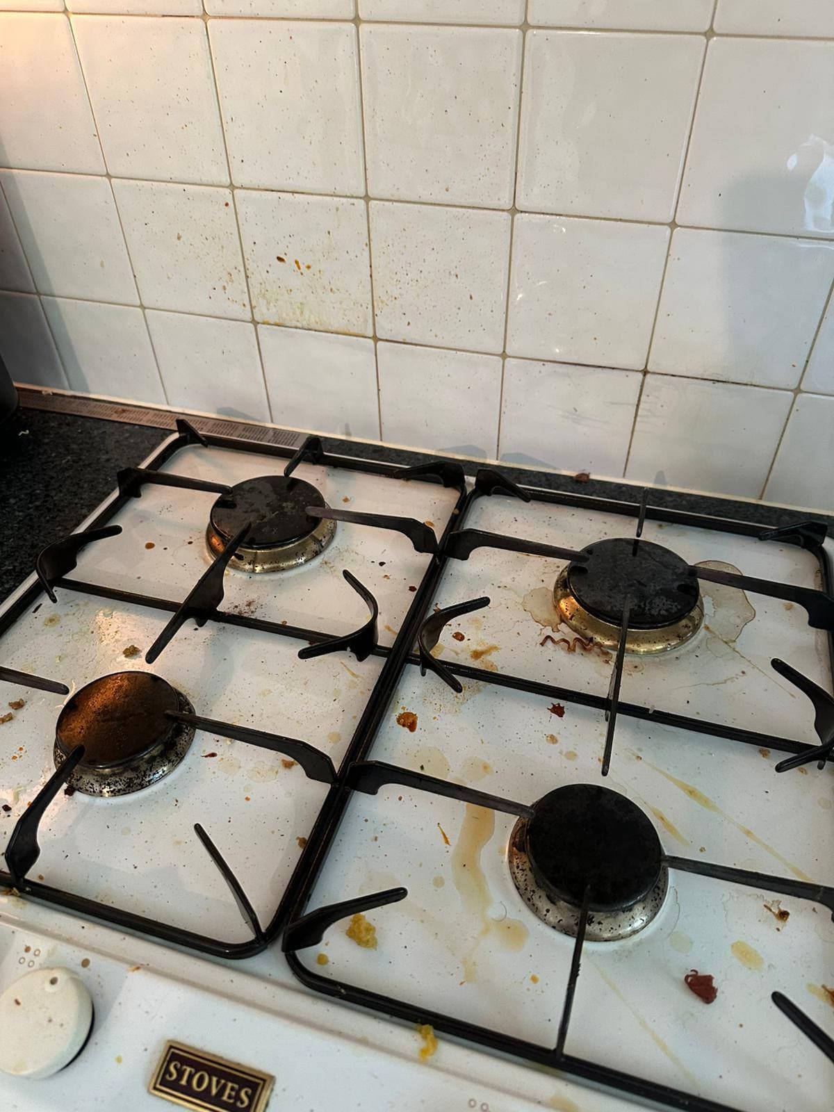 White gas hob with burnt-on grease, food spills and heavily stained pan supports before cleaning